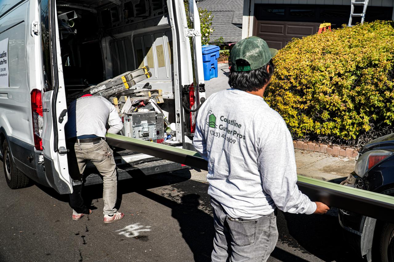 Coastline installers loading a seamless aluminum gutter into a truck on a LA street.