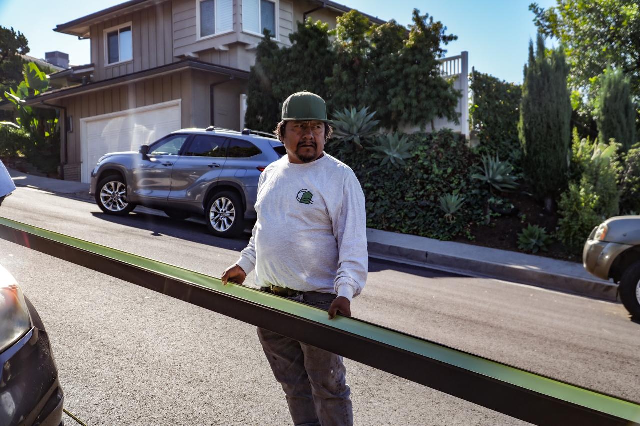 Coastline installer with downspout sections on a Los Angeles property.